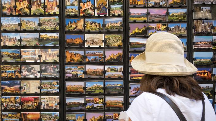 A tourist looks at postcards during her visit to medieval fortified city of Carcassonne, southern France on July 2, 2018. (Photo by ERIC CABANIS / AFP)